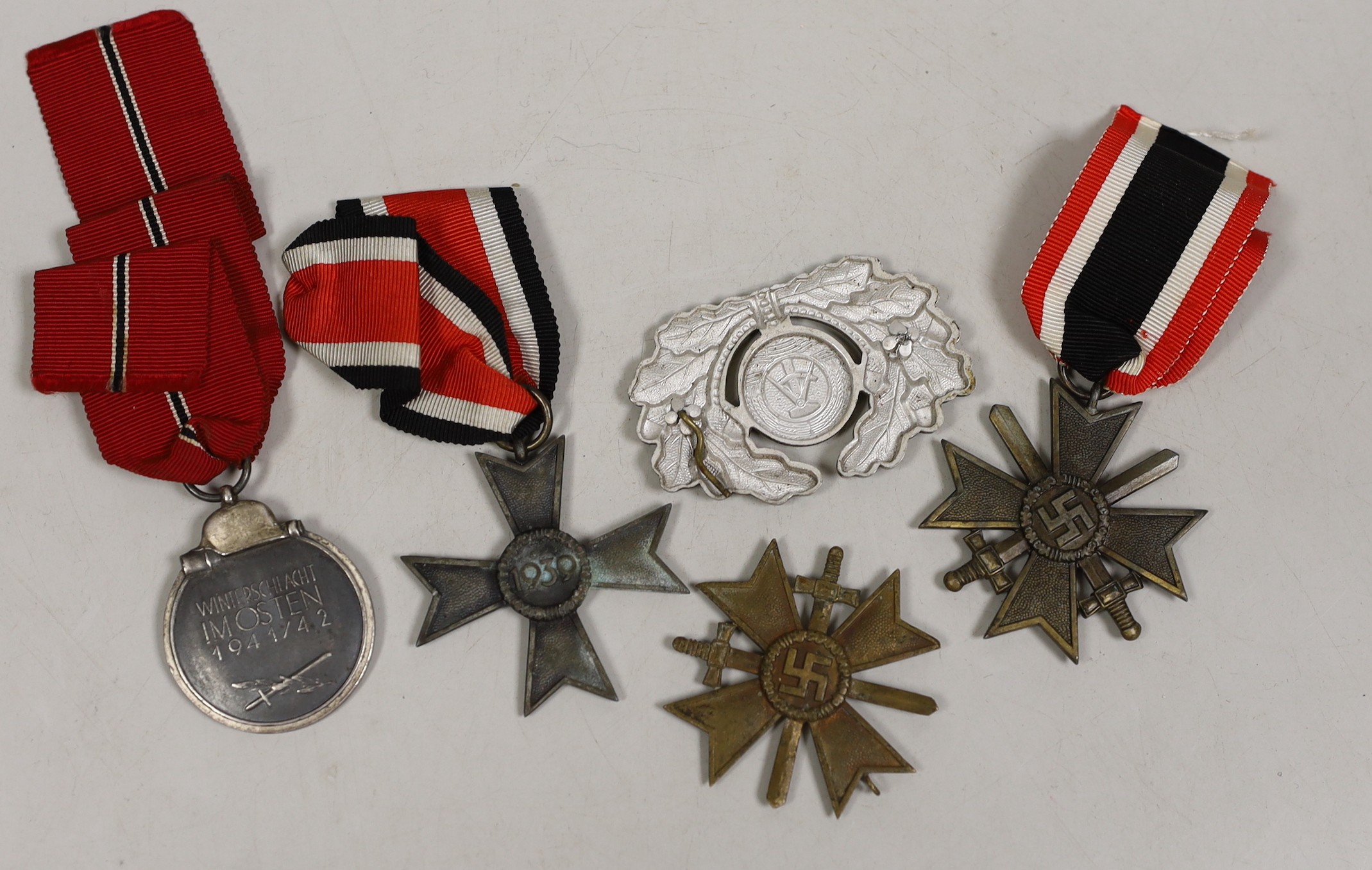 Four German Third Reich medals, comprising three merit crosses, and a Winterschlacht medal, together with a Russian cap badge.